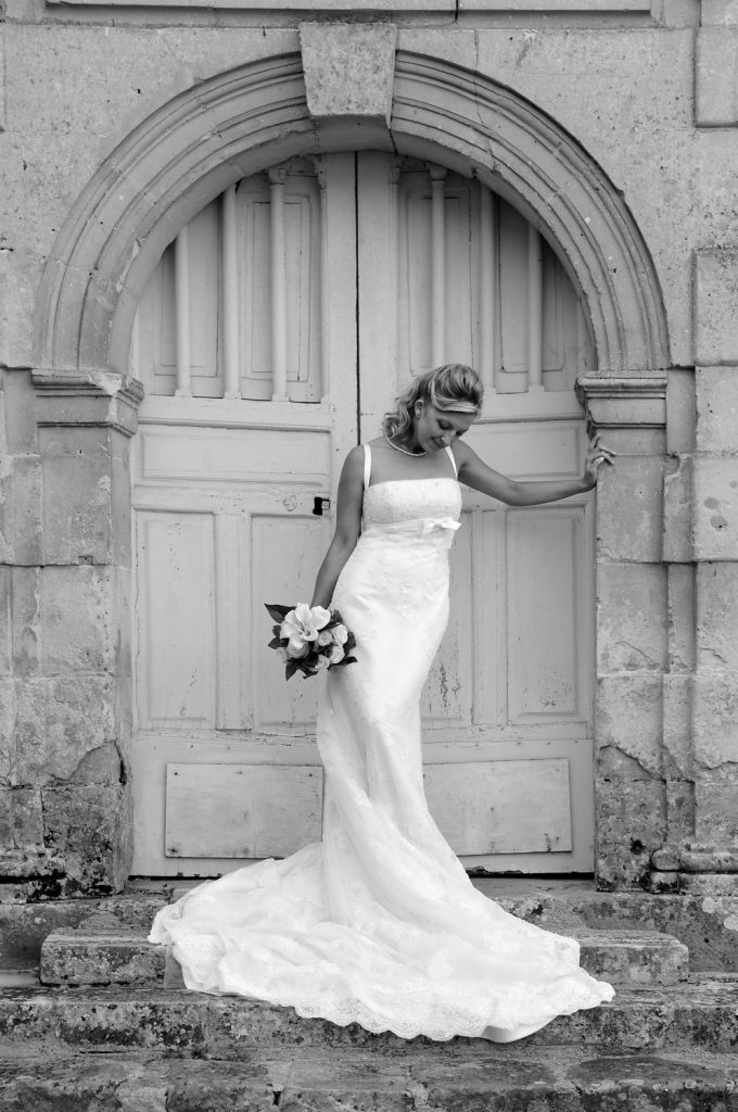 Mariée portant un bouquet, accoudée à une porte
